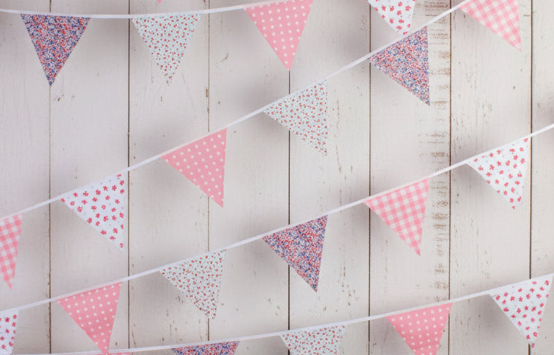 String of colorful floral flags on a white fence